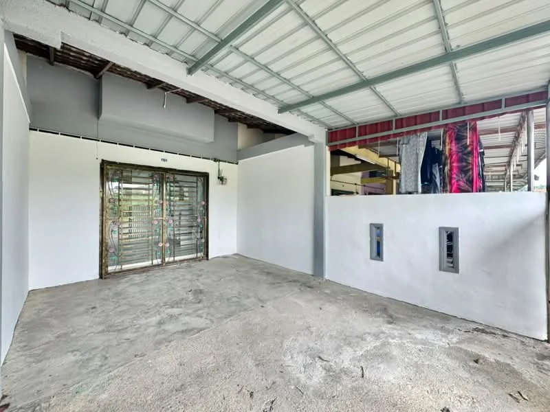 Room features: concrete flooring, white painted walls, metal roof, sliding metal gate, two wall-mounted electrical outlets, exposed ceiling beams, laundry area with clothes hanging, open layout; style: modern.