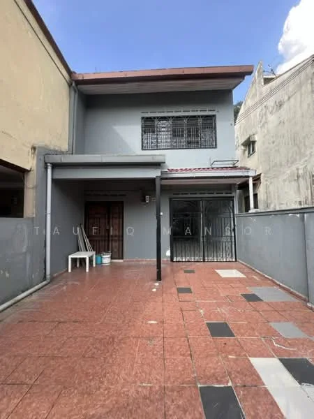 Exterior type: semi-detached house; features: grey painted facade, flat roof, single-storey, paved outdoor area with mixed tiles, covered porch, large sliding glass door, window grilles, exposed brick wall, surrounded by neighboring buildings; style: modern.