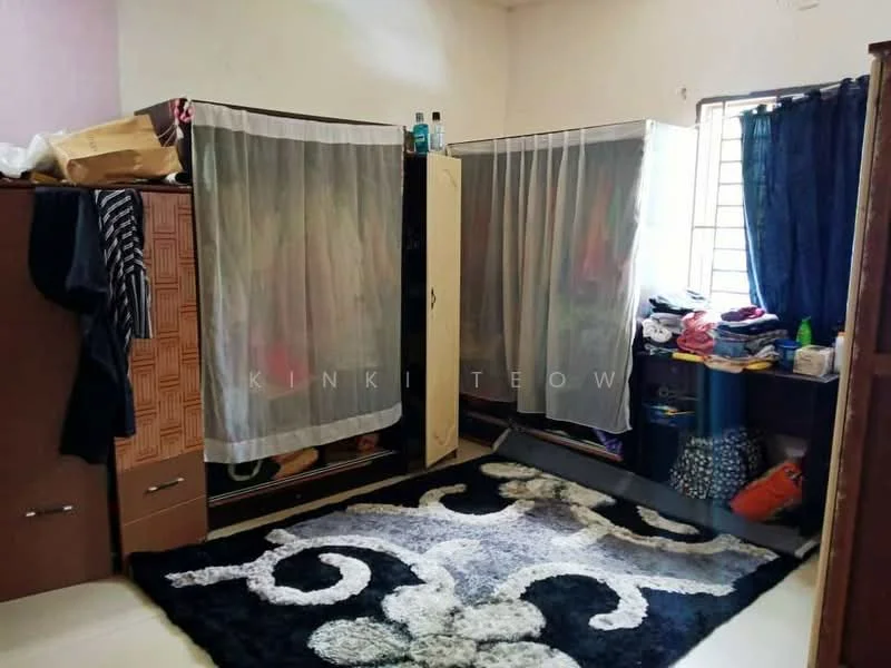 Room features: carpet with abstract pattern, wardrobe with sliding doors, curtains on window, clothes stored on shelves, plastic storage container, clothes hanging behind curtains, wooden cabinet, wall-mounted items.