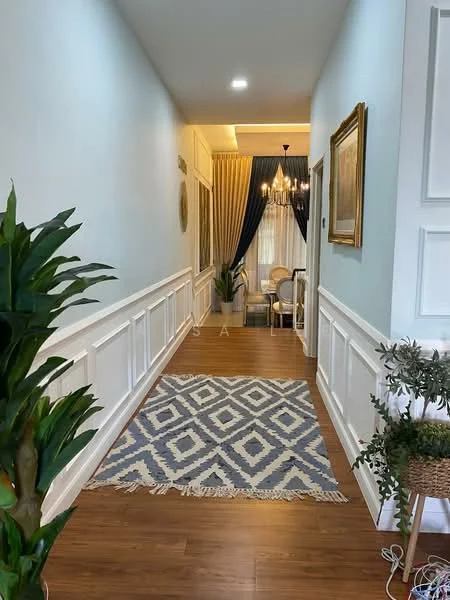 Hallway features: light blue painted walls, white wainscoting, wood laminate flooring, chandelier with multiple bulbs, decorative framed artwork, area rug with geometric pattern, green potted plant, curtains in dark blue fabric, seating area visible at the end of the hallway; style: modern.
