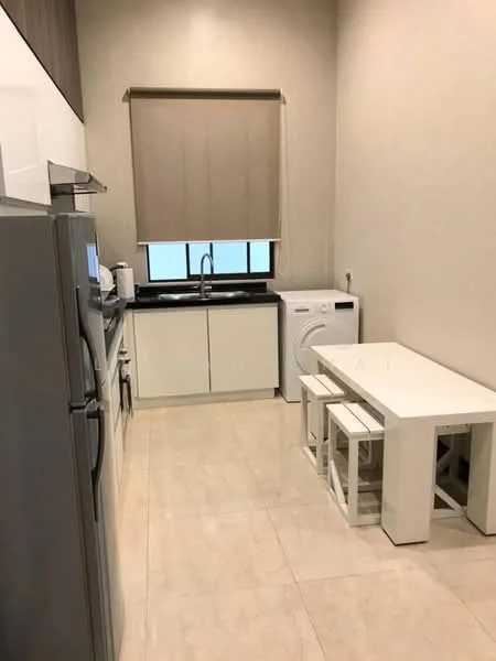 Kitchen features: white cabinetry, black countertop, single-bowl stainless-steel sink, chrome pull-down faucet, built-in microwave, stainless-steel fridge, freestanding washing machine, tile flooring, window with roller blinds, dining table with four stools; style: modern.