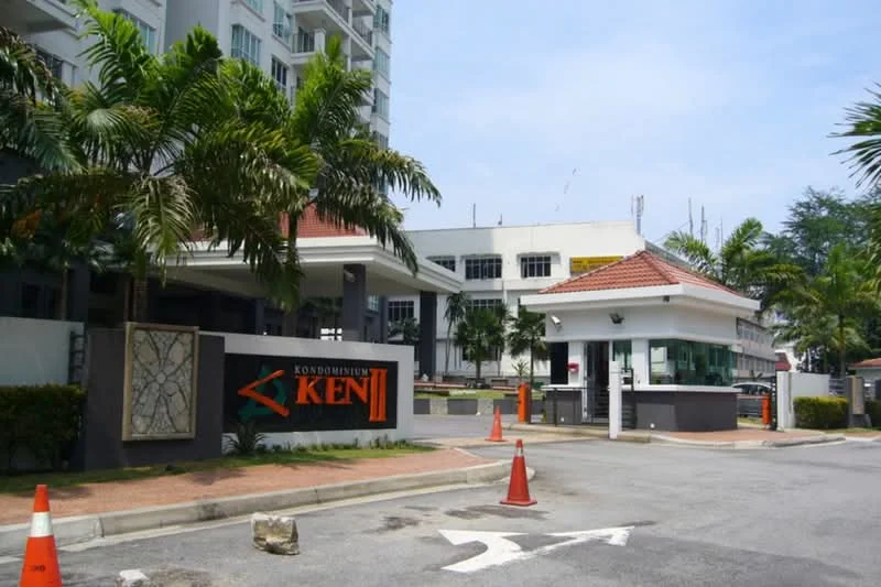 Exterior type: condominium; features: guard house at entrance, paved driveway, landscaped greenery, signage with name 'KEN II', tropical landscaping with palm trees, parking area, surrounded by mature trees; style: modern.