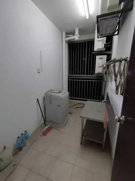 Laundry features: white washing machine, grey table, tile flooring, white painted walls, window with metal grille, bottled water, cleaning supplies, light fixtures on ceiling.
