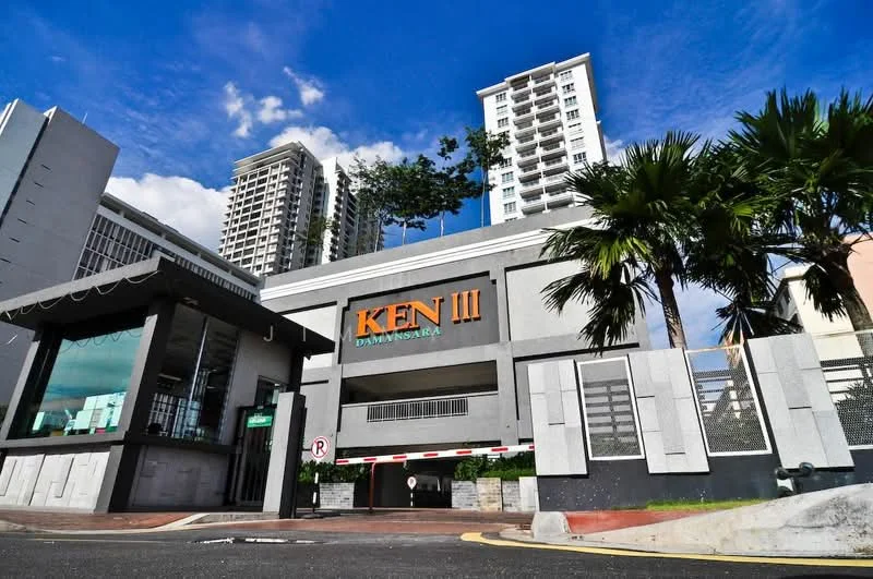 Exterior type: high-rise condominium; features: grey painted facade, glass entrance, signage with 'KEN III', surrounding palm trees, multi-storey building in background, guard house at entrance, gated entry, landscaped surroundings; style: modern.
