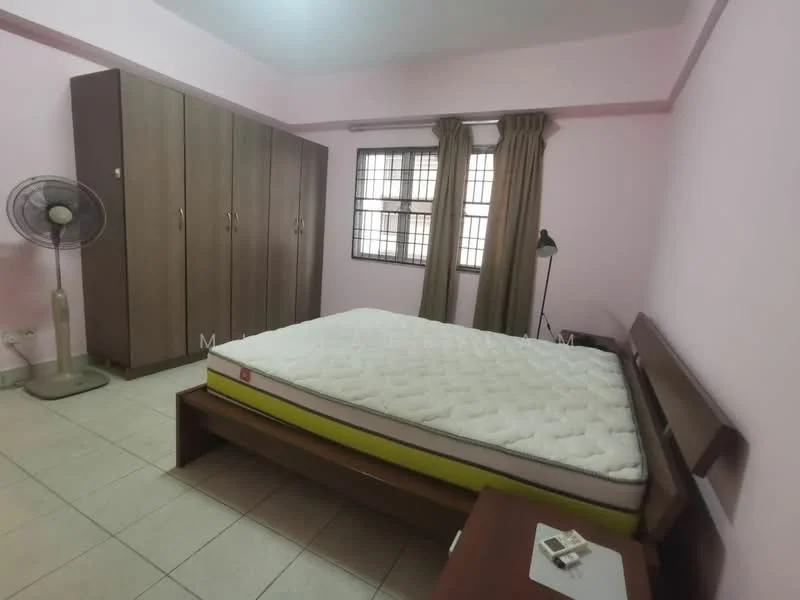 Bedroom features: pink painted walls, tiled flooring, queen-size bed with mattress, wooden bed frame, wooden wardrobe with sliding doors, floor fan, table lamp, curtains on windows, nightstand, window with grid pattern.