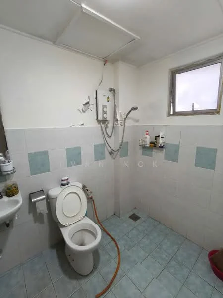 Bathroom features: white tiled walls with blue accents, light blue ceramic tile flooring, one-piece toilet, wall-mounted shower head, water heater unit, small window for natural light, sink with wall-mounted faucet, toilet paper holder.