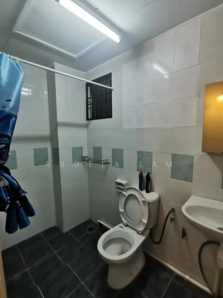 Bathroom features: white tiled walls, grey tiled flooring, one-piece toilet, sink with wall-mounted faucet, mirror above sink, shower area with glass partition, blue shower curtain, exposed plumbing, ceiling lights.