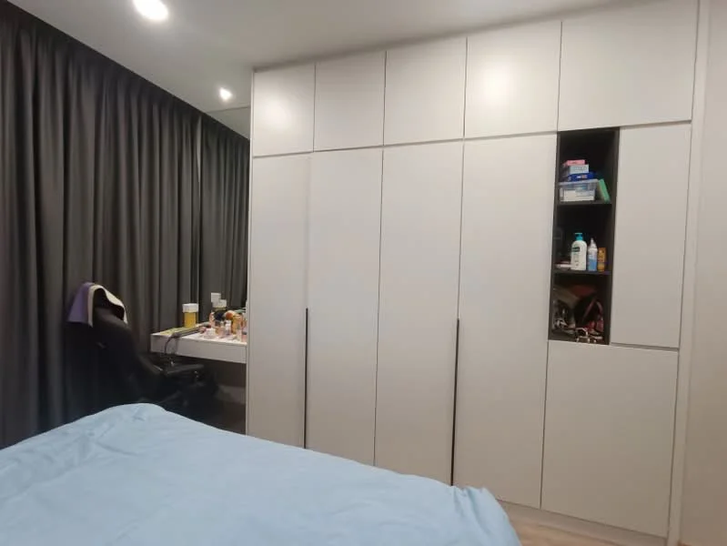 Bedroom features: light blue bedding, built-in wardrobe with white finish, desk with chair, grey curtains, recessed lighting, wooden flooring, shelves with various items, neutral wall color; style: modern.