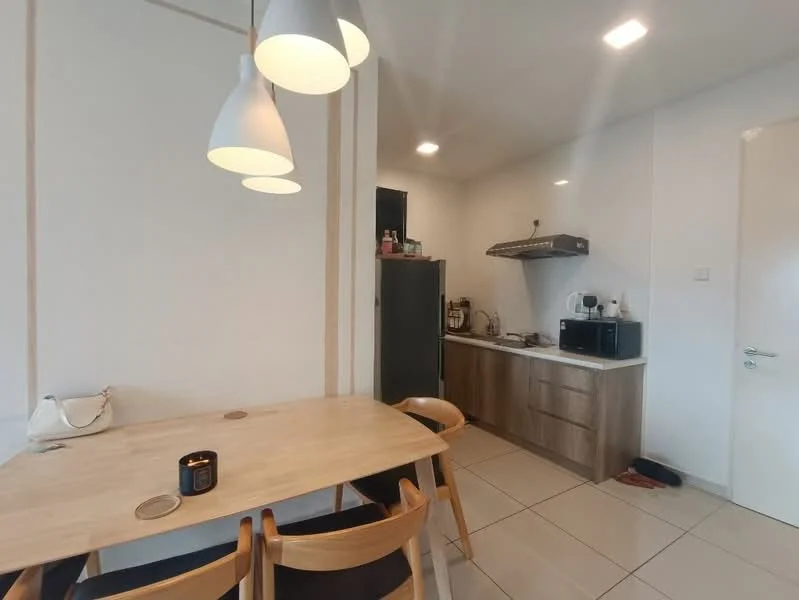 Kitchen features: light wood cabinetry, stainless-steel fridge, built-in oven, stainless-steel range hood, ceramic tile flooring, white walls, pendant lighting, kitchen countertop, microwave, dining table with wooden chairs, black candle on table; style: modern.