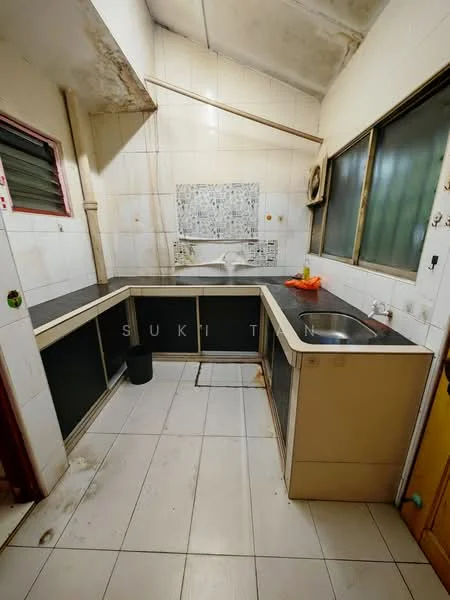 Kitchen features: L-shaped kitchen layout, black countertop, cream cabinetry, single-bowl stainless-steel sink, chrome faucet, wall-mounted air conditioning unit, white tiled walls, white tiled flooring, window with green view, exposed ceiling, decorative backsplash with mosaic pattern, trash bin.
