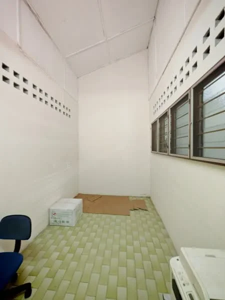 Room features: white painted walls, sloped ceiling, green ceramic tile flooring, two windows with horizontal bars, cardboard box on floor, blue office chair, air conditioning unit.