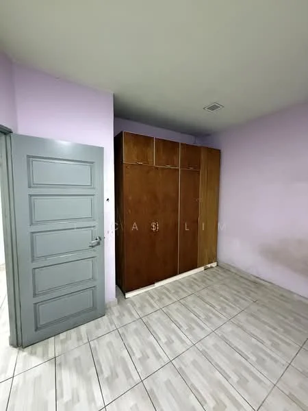 Room features: light purple painted walls, white tiled flooring, wooden wardrobe with sliding doors, grey door, ceiling light, corner with wall stains.