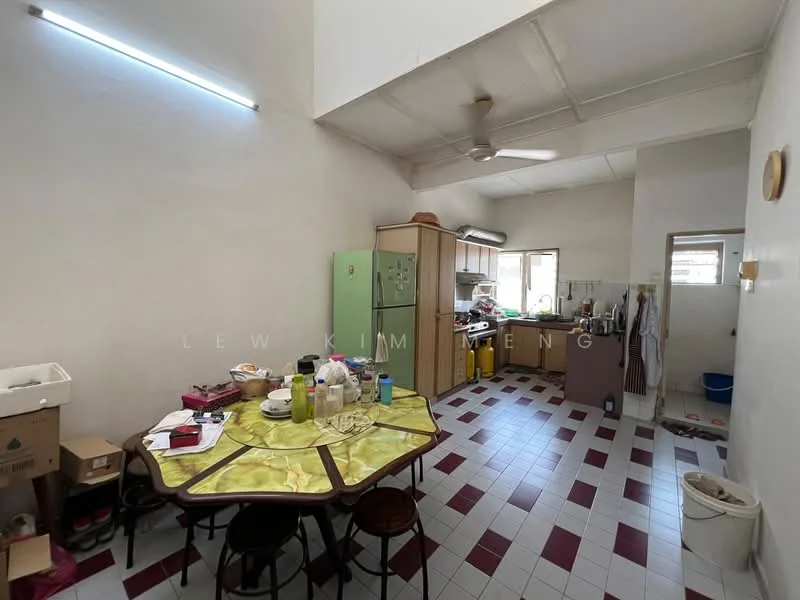 Kitchen features: green refrigerator, wood cabinetry, white tiled backsplash, stainless-steel sink, chrome faucet, 4-burner gas hob, built-in oven, window with natural light, ceiling fan, table with yellow tablecloth, dining chairs, red and white tiled flooring, open shelving, various kitchen appliances, boxes for storage.