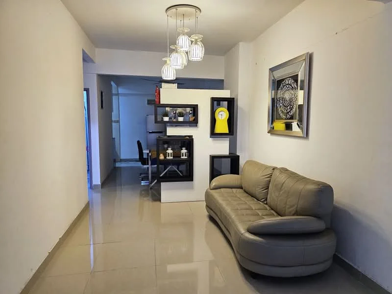 Living features: grey leather sofa, polished ceramic tile flooring, white painted walls, recessed downlights, pendant light fixture with multiple bulbs, decorative wall mirror, open shelving unit, black storage cabinet, dining table visible in background, office chair visible in background; style: modern.