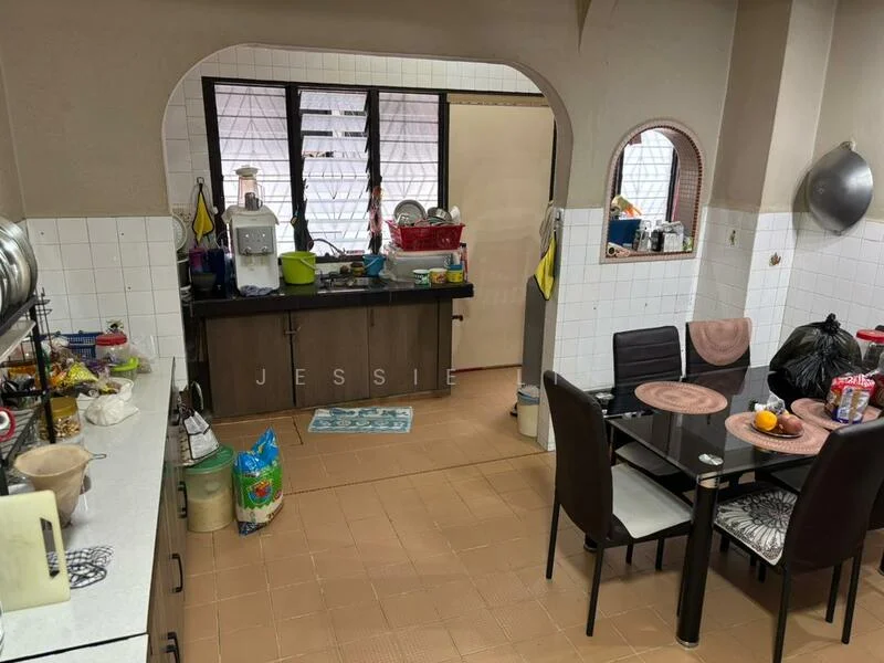 Kitchen features: L-shaped countertop with white tiles, brown cabinetry, stainless-steel sink, chrome faucet, built-in kitchen appliances, black dining table with four chairs, flooring with beige tiles, window with sheer curtains, open layout to dining area, various kitchen utensils and containers visible, refrigerator, wall-mounted shelves.