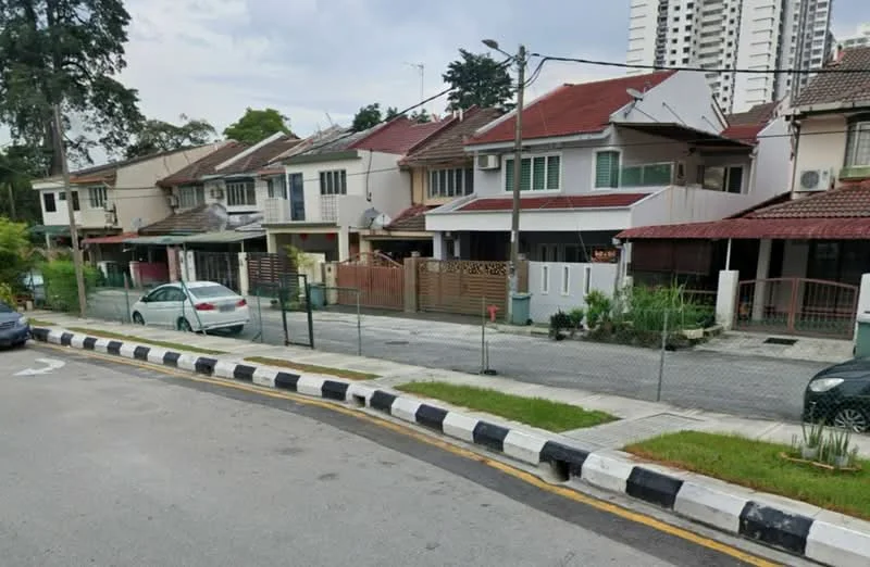 Exterior type: linked terrace house; features: red tiled roof, white painted facade, front yard with fencing, driveway with interlocking pavers, mature trees in vicinity, street view with parked cars, single-storey, visible windows with green shutters; style: traditional.
