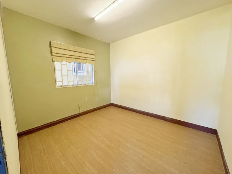 Room features: light brown laminate flooring, green painted walls, white ceiling, window with grid pattern, window treatment with fabric blinds, no visible furniture or decor; style: minimalist.