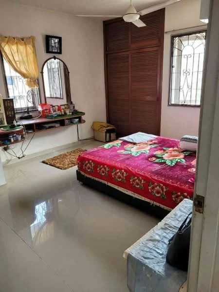 Bedroom features: queen-size bed with floral bedspread, wooden wardrobe with sliding doors, wall-mounted mirror, shelves with decorative items, window with metal grille, curtains in yellow, area rug, polished tile flooring, ceiling fan.