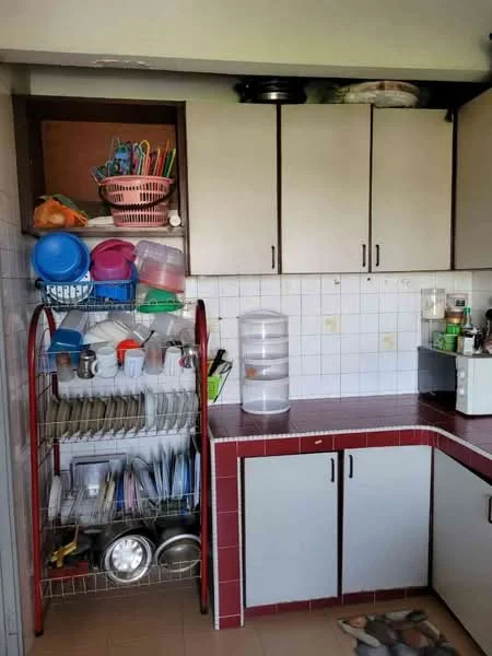 Kitchen features: white cabinetry, red countertop, stainless-steel sink, microwave, dish rack with plates and cups, open shelving with utensils, tile backsplash, floor tiles, kitchen mat.