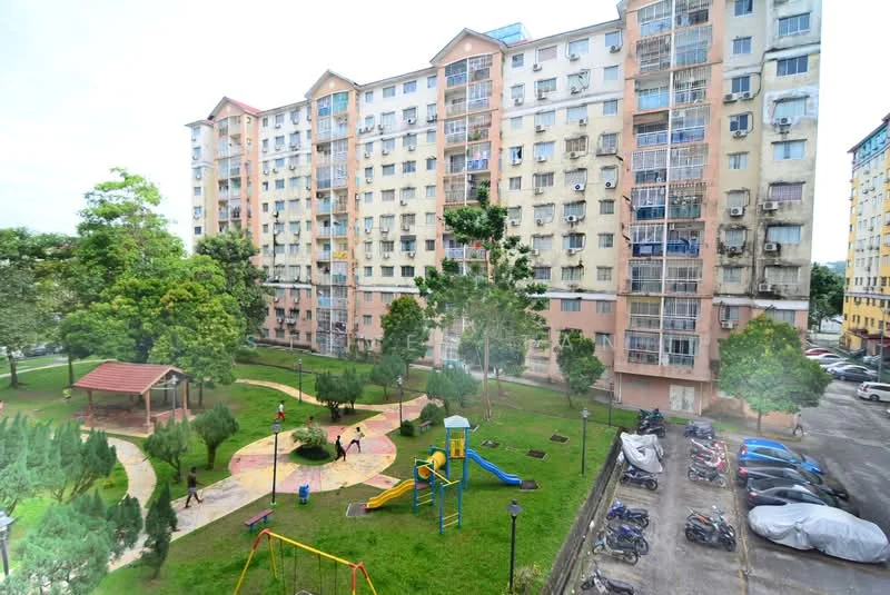 Exterior type: low-rise apartment block; features: pink and cream painted facade, multiple floors with balconies, landscaped garden with trees, children's playground with swings and slides, paved walking paths, open green spaces, parking area with visible vehicles; style: modern.