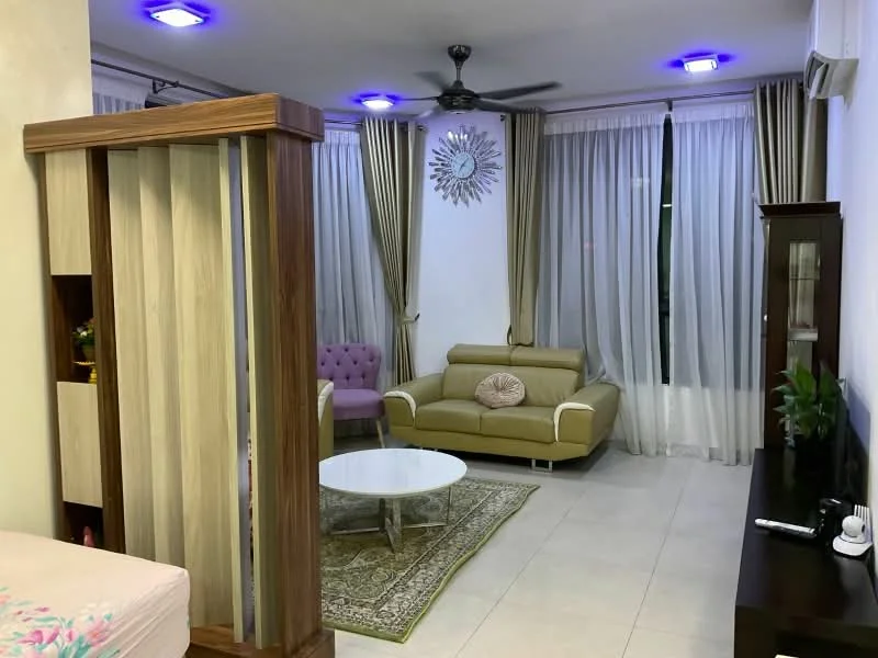 Living features: cream painted walls, white ceiling, 5-blade ceiling fan with light, floor-to-ceiling windows with sheer curtains, light grey tiled flooring, green area rug with geometric pattern, 2-seater leather sofa in light green, purple upholstered armchair, round white coffee table, decorative wall mirror, TV console, indoor plants; style: modern.