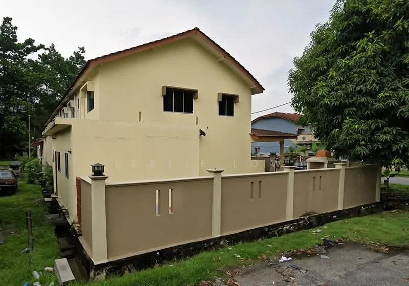 Exterior type: semi-detached house; features: yellow painted facade, flat roof, two-storey structure, fenced perimeter wall, garden area with grass, driveway, windows with grills, mature trees nearby; style: modern.