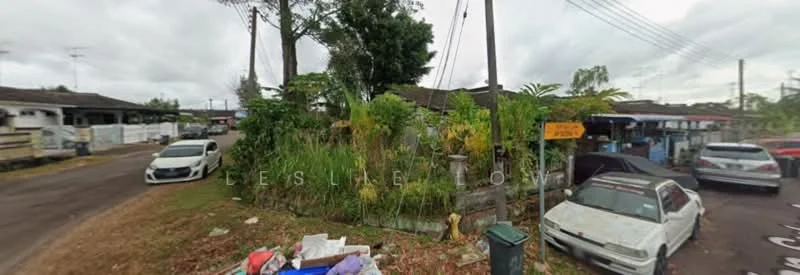 Exterior features: overgrown grass, mature trees, street view, parked cars, garbage bins, roadside signage, residential buildings in background.