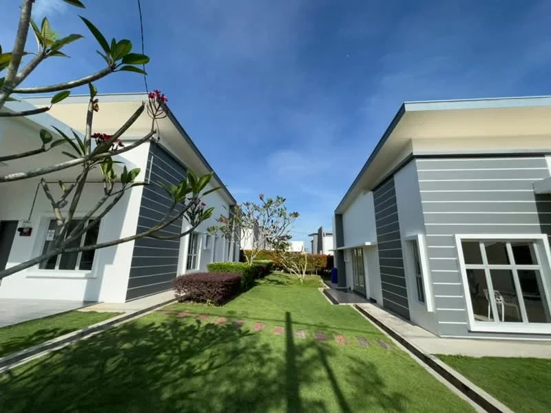 Exterior type: linked terrace house; features: white painted facade, grey horizontal cladding, manicured lawn, landscaped garden with shrubs, paved walkway, single-storey, large windows, outdoor lighting, surrounded by greenery; style: modern.