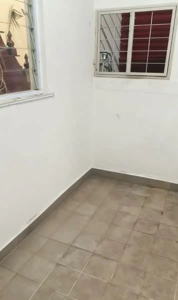 Room features: white painted walls, grey tiled flooring, small window with metal grille, corner space.