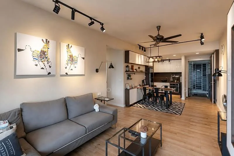 Living features: 3-seater fabric sofa in grey, glass coffee table, area rug with geometric pattern, wall-mounted TV, track lighting, 5-blade ceiling fan with light, framed artwork with animal prints, open shelving, wooden flooring, decorative wall sconce; style: modern. Kitchen features: white cabinetry, stainless-steel appliances, black countertop, kitchen island with seating, recessed downlights, open-plan layout; style: modern.