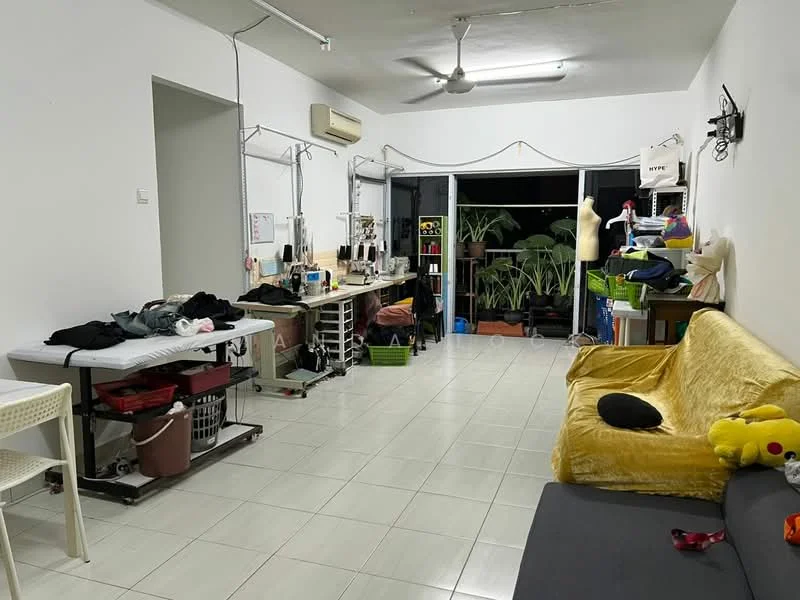 Living features: white painted walls, tile flooring, 5-blade ceiling fan, sofa in grey, yellow throw blanket, coffee table, work tables with sewing machines, storage shelves, potted plants, laundry basket, decorative pillows.