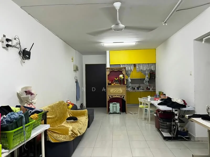 Living features: yellow cabinetry, white painted walls, grey tiled flooring, sofa with yellow throw, ceiling fan, dining table with chairs, laundry basket, open kitchen layout, wall-mounted TV, clothes on drying rack, decorative items on shelves.