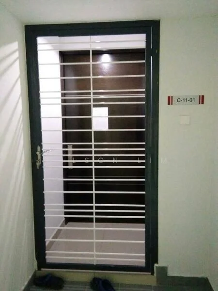 Room features: metal security gate with horizontal bars, dark wooden door, light-colored wall, tile flooring, door number plate, light fixture above door, slippers on floor; style: modern.