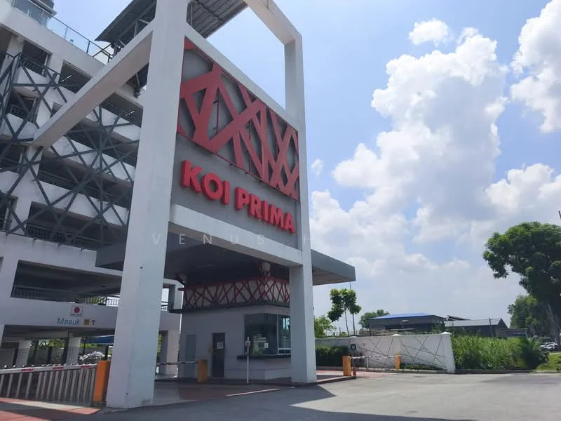 Exterior type: low-rise apartment block; features: white painted facade, red signage with 'KOI PRIMA', open-air parking lot, covered entrance, landscaped greenery, surrounded by mature trees, clear blue sky, modern architectural design; style: modern.