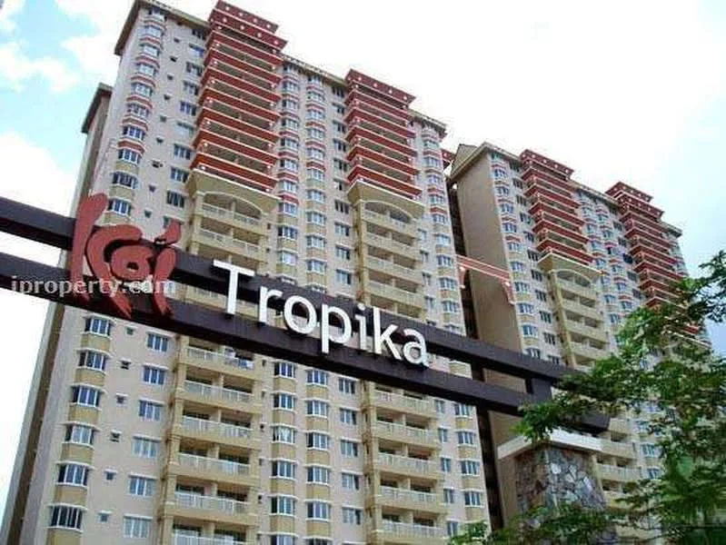Exterior type: high-rise condominium; features: cream painted facade, red accent balconies, glass railing on balconies, multiple storeys, landscaped entrance, signage with name 'Tropika', surrounded by greenery, modern architectural design; style: modern.
