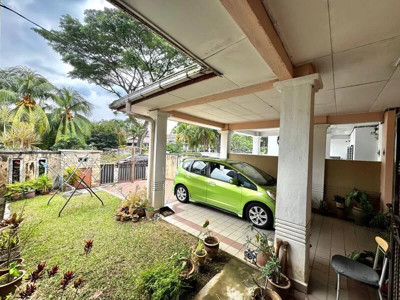 Exterior type: detached bungalow; features: green car parked in driveway, manicured lawn, paved walkway, swing set in garden, potted plants, covered porch area, white painted columns, overhead lighting fixtures, surrounding greenery; style: traditional.