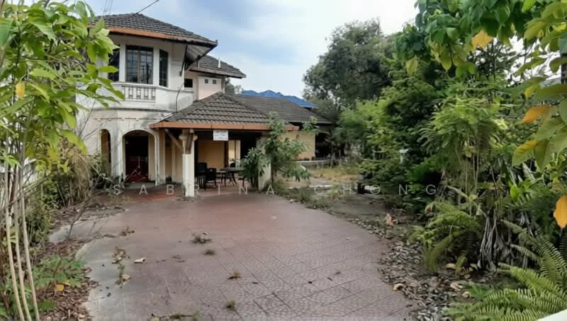 Exterior type: detached bungalow; features: single-storey, tiled flooring in patio area, gabled roof with tiles, surrounded by greenery, mature trees, overgrown landscaping, front porch area, driveway with interlocking pavers; style: traditional.