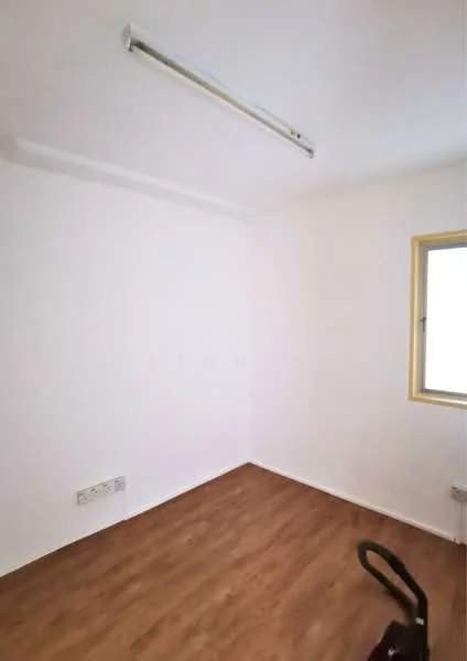 Room features: white painted walls, laminate flooring, single window, ceiling light fixture, vacuum cleaner visible.