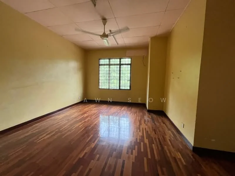 Room features: yellow painted walls, wooden flooring, ceiling fan, large window with grid pattern, natural light, corner of the room with no visible furniture, plain ceiling, no visible decor.