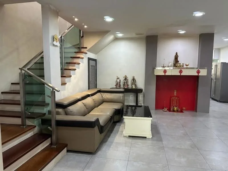 Living features: L-shape sectional sofa in beige and brown, coffee table with black top and white base, tile flooring in light grey, recessed downlights, decorative wall with red accent, staircase with glass railing, decorative statues on shelf, wall-mounted decor, open layout to staircase; style: modern.