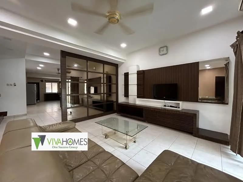 Living features: cream painted walls, white ceiling, 5-blade ceiling fan with light, large glass coffee table, wall-mounted TV, built-in cabinetry with dark wood finish, light-colored floor tiles, curtains in neutral tone, decorative wall clock; style: modern. Room features: open layout to adjacent room, visible kitchen area in background.