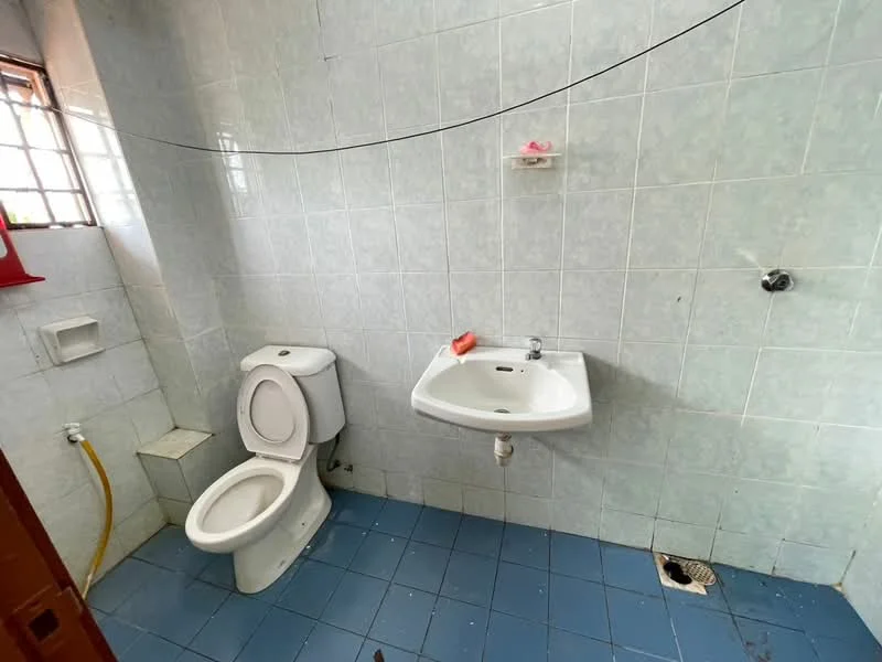 Bathroom features: white ceramic toilet, white wall-mounted sink, blue ceramic floor tiles, light blue wall tiles, shower faucet, soap dish, drain in floor, window for natural light.