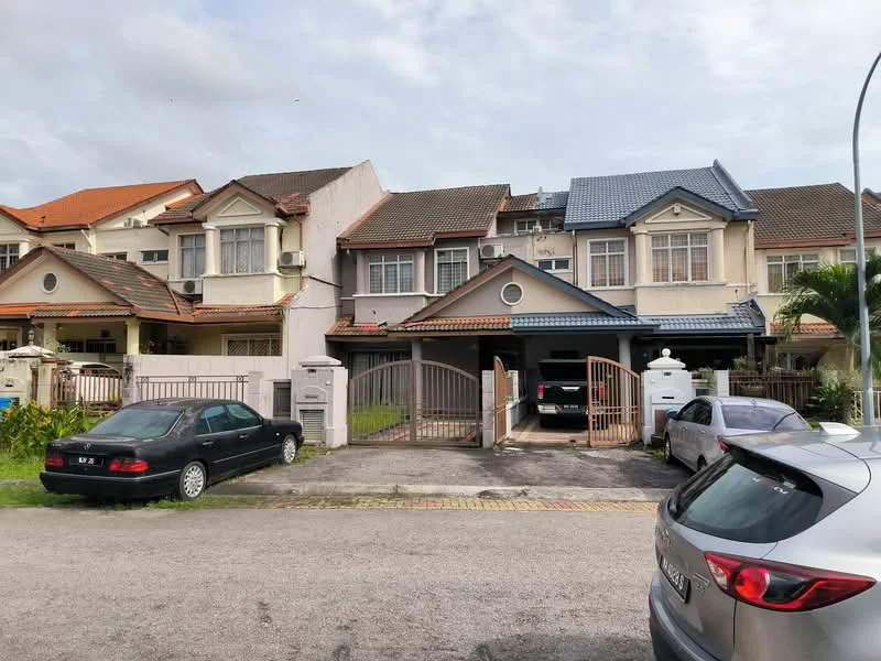 Exterior type: linked terrace house; features: two-storey building, grey painted facade, gabled roof with tiles, front porch with gate, manicured lawn, driveway with interlocking pavers, visible car parked in driveway, surrounded by other residential buildings, windows with grilles, air conditioning unit visible on facade; style: modern.