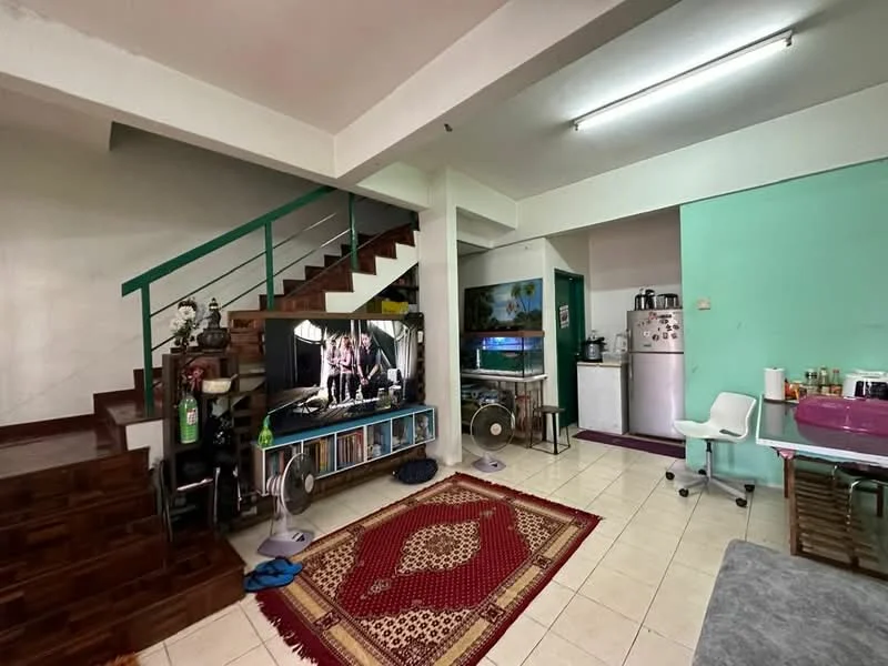 Living features: white painted walls, tile flooring, 5-blade ceiling fan, wall-mounted TV, wooden staircase, area rug with geometric pattern, bookshelf, two standing fans, dining table with chairs, refrigerator, kitchen counter with appliances; style: modern.