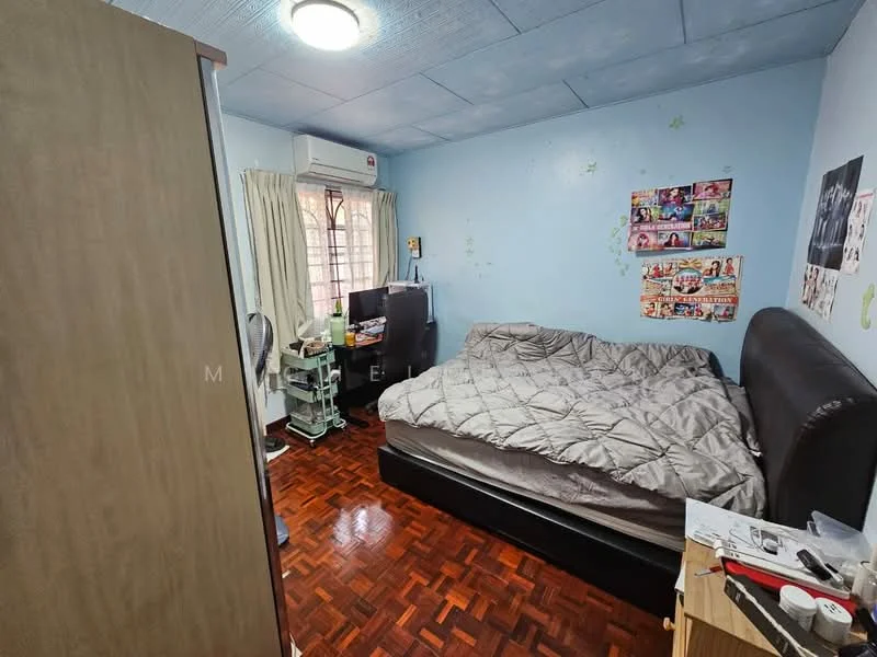 Bedroom features: queen-size bed with grey bedding, wooden headboard, parquet wood flooring, light blue painted walls, window with sheer curtains, wall-mounted air conditioning unit, desk with computer setup, built-in wardrobe, decorative wall posters, table with miscellaneous items.