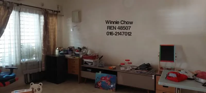 Room features: light beige painted walls, cream-colored curtains, floor-to-ceiling windows, wooden sideboard, multiple storage cabinets, various kitchen utensils visible, children's toys, carpeted flooring, air conditioning unit.