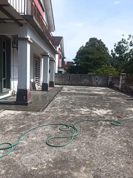 Exterior type: detached bungalow; features: concrete driveway, manicured lawn, surrounding greenery, fenced perimeter, balcony on upper level, outdoor hose, flat roof, single-storey, paved walkway, exposed concrete surface; style: traditional.