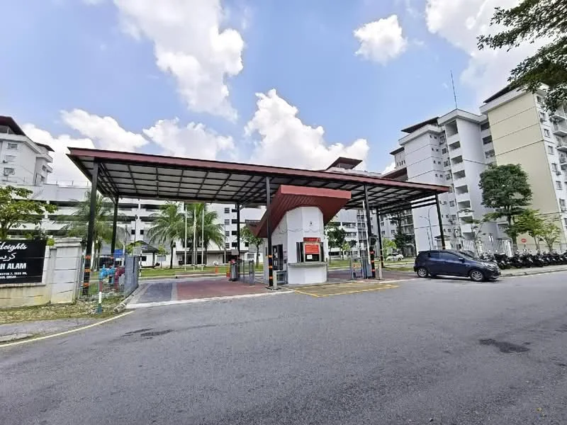 Exterior type: low-rise apartment block; features: covered entrance with awning, security guardhouse, paved driveway, landscaped greenery, multiple parking spaces, surrounding palm trees, residential buildings in background, open-air parking area; style: modern.