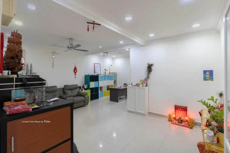 Living features: grey leather sofa, ceiling fan, recessed LED downlights, white painted walls, glossy tile flooring, decorative wall art, colorful storage cabinets, small decorative altar, wall-mounted decorations, open layout, corner table, potted plants; style: modern.