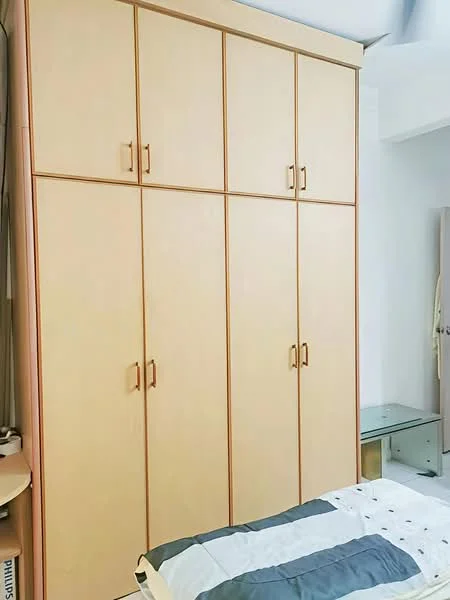 Bedroom features: built-in wardrobe with multiple doors, light wood cabinetry, neutral wall colour, bed with patterned bedding, glass side table, flooring not visible; style: modern.